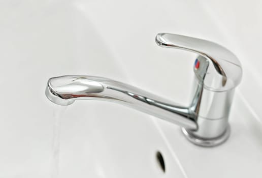 Chrome faucet tap with water flowing, closeup detail