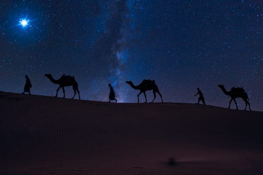 Christmas Jesus birth concept - Adoration of the Magi, Three Wise Men, Three Kings, and the Three biblical Magi with camel silhouettes journeying in sand dunes of desert follow Bethlehem star at night