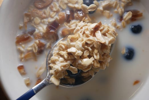 Warm oatmeal served with nuts and blueberries in a cozy kitchen setting.