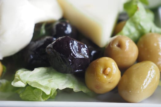 Colorful assortment of olives and greens arranged artistically on a plate.
