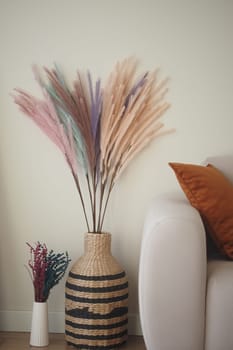 Colorful dried flowers arranged in a stylish vase by a sofa.