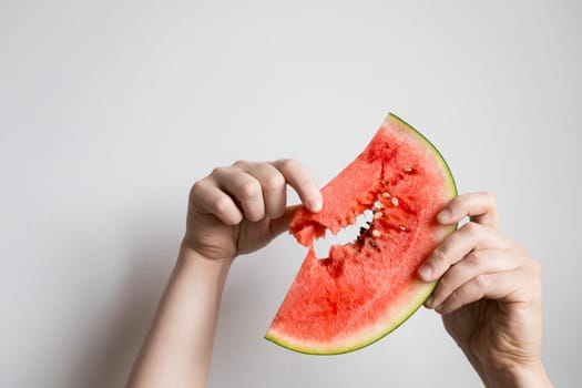 Caucasian hands holding juicy watermelon slice against white background.