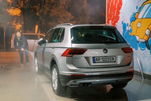 Driver washes his car with a hose at a self-service car wash. High quality photo