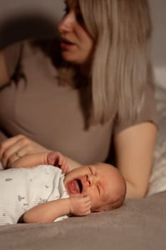 A mother lovingly holds her crying baby, providing comfort and warmth, as they enjoy a quiet moment together at home in the evening.