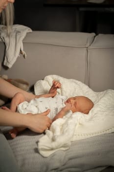A mother lovingly supports her baby who is resting on a warm, fluffy blanket in a comfortable living room setting during the afternoon.