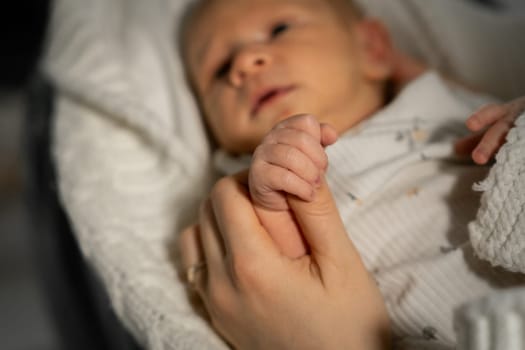 A mother cradles her babys tiny hand in a warm and intimate setting as they share a comforting moment together, reflecting love and tenderness.