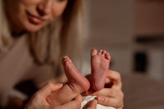 A mother lovingly cradles her babys small feet in a warm, intimate setting, creating a special bond in the early evening light.