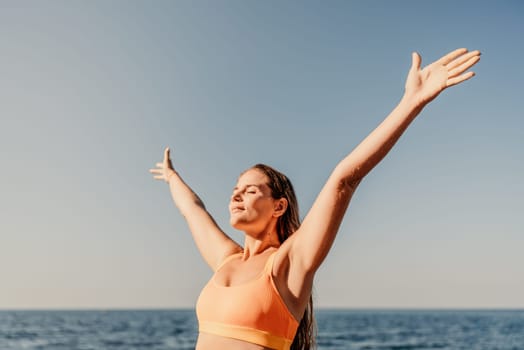 A woman with long hair is standing in the sun, with her arms raised in the air. Concept of freedom and joy, as the woman is celebrating or expressing happiness. The bright blue sky