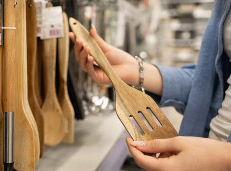 Girl In A Store Picks A Wooden Spatula In Close-Up
