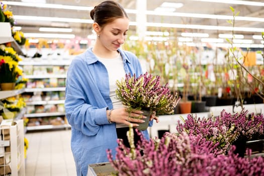Girl In Supermarket Choosing Potted Flowers In The Flower Department