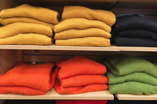 A row of folded sweaters on a shelf in the store