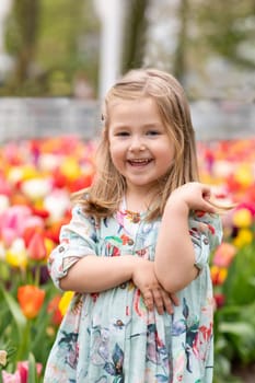 Happy girl laughs in a park with the tulips