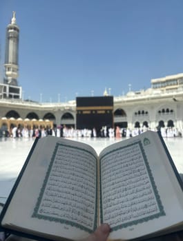 Mekkah, Saudia Arabia, 02 May 2024, A Quran reading in front of the Kaaba at Masjid al-Haram, Mecca, Saudi Arabia. Worshippers perform Tawaf around the sacred site under a clear blue sky, symbolizing faith and devotion in Islam.