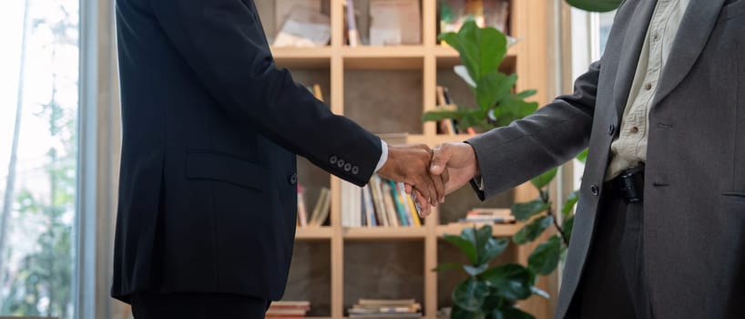 Two senior professionals engage in a firm handshake, symbolizing mutual agreement and collaboration in a professional environment.
