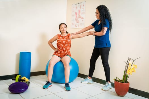 Physiotherapist woman with patient sitting on rehabilitation ball. Physiotherapist assisting female patient sitting on rehabilitation ball. Rehabilitation therapy with fitness ball