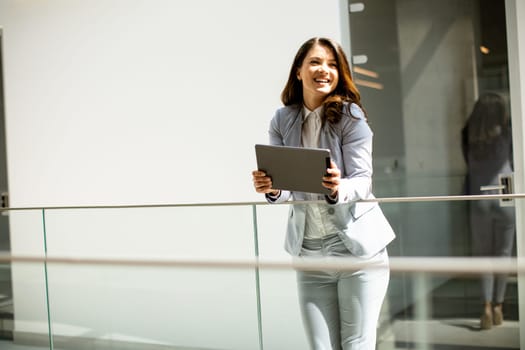 Pretty young woman working on digital tablet in the office hallway