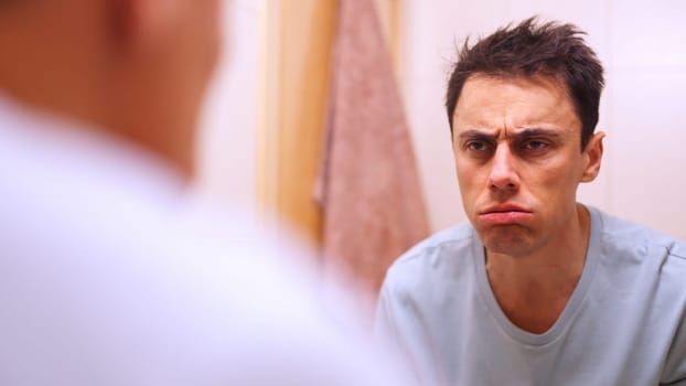 Employee looking at himself in the mirror with a disgusted expression, not wanting to go to work on monday morning