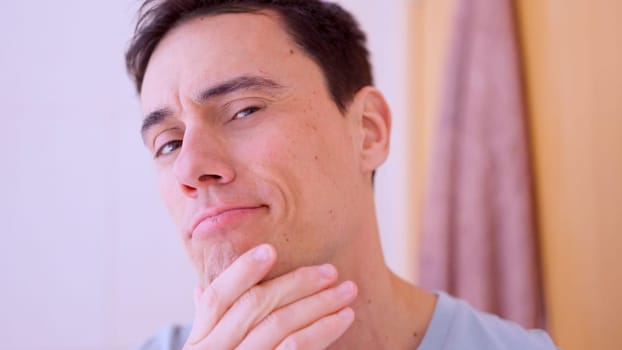 Man in bathroom stroking his chin, lost in thought and contemplating decisions