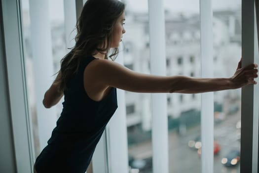 Pretty young woman in underwear standing by window in the room
