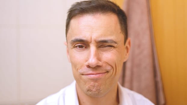 Man winking and smiling while getting ready in his bathroom in the morning