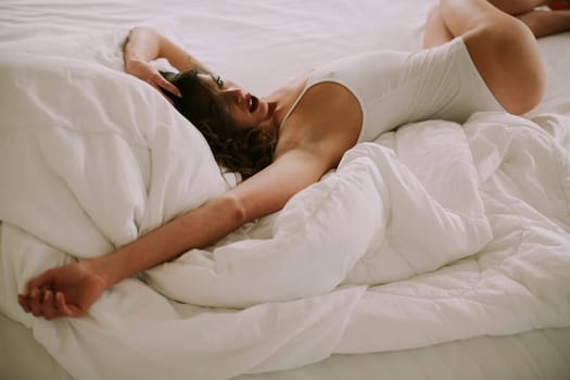 Attracttive young woman lies in white bed