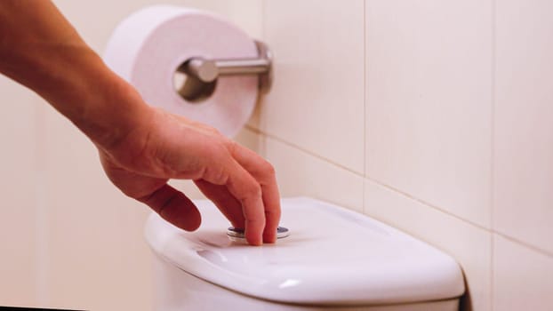 Close up of a hand flushing a white toilet