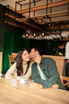 Two friends share laughter and warm drinks at a charming cafe, creating an inviting atmosphere that celebrates connection and joy during a sunny day