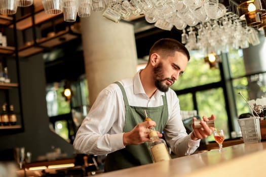 Bartender concentrates as he skillfully crafts a cocktail, surrounded by an array of glassware in a modern bar filled with natural light, creating an inviting atmosphere