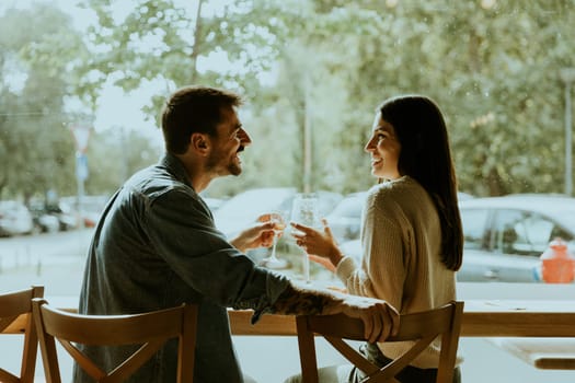 Two individuals share laughter and engaging conversation while savoring a delicious meal at a charming cafe, with trees and cars in the background.