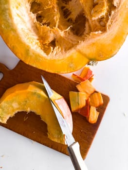 Fresh pumpkin being sliced on cutting board for autumn cooking preparation.