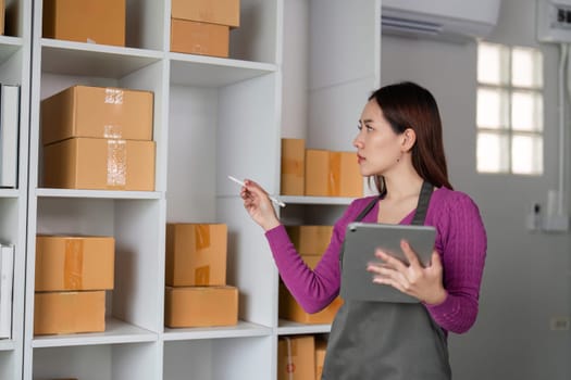 An online seller organizes products in a warehouse, utilizing a tablet and pen to track inventory and ensure efficient order fulfillment.