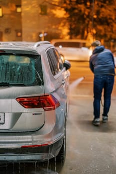 Man washing a car with a hose at a self-service car wash. High quality photo
