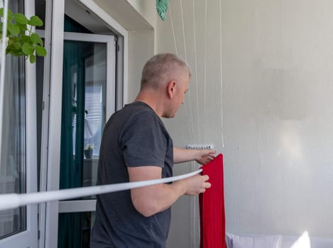 Man hangs the clothes on the roller dryer on the balcony