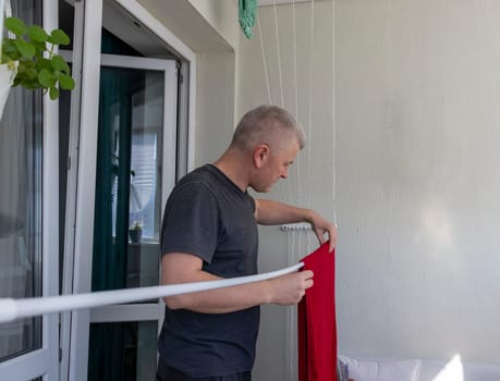 Man hangs the clothes on the roller dryer on the balcony