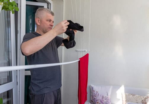 Man hangs the clothes on the roller dryer on the balcony