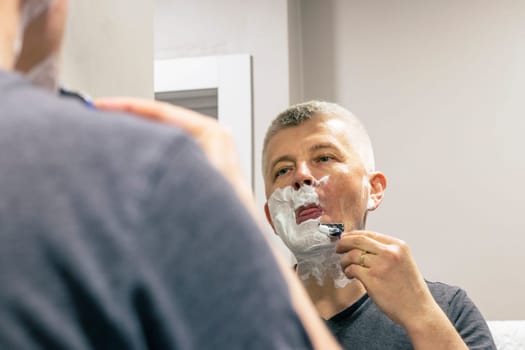 Reflection in the mirror of the man shaving