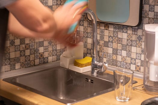 Man cleaning and polishing the kitchen faucet