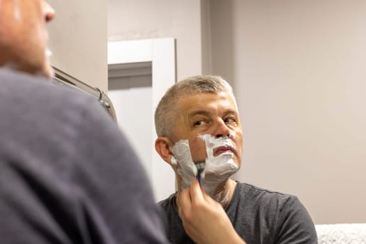 Reflection in the mirror of the man shaving