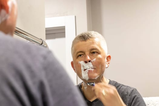 Reflection in the mirror of the man shaving