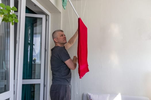 Man hangs the clothes on the roller dryer on the balcony