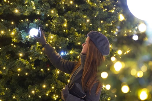 In her grey coat and iconic beret, a Parisian woman gazes fondly at Christmas decorations on a tree, surrounded by the enchanting spirit of New Year festivities in a wintry Paris setting