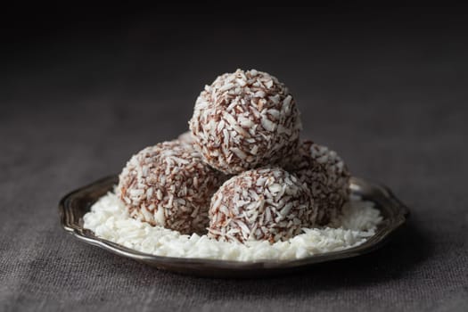 Artisan chocolate coconut truffle candies on dark background from confectionary. Handmade or handcrafted bonbons, chocolatier concept. Horizontal banner, copy space