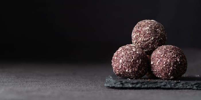 Artisan chocolate truffle candies with berry and fruit filling on dark marble background from confectionary. Handmade or handcrafted bonbons, chocolatier concept. Horizontal banner, copy space