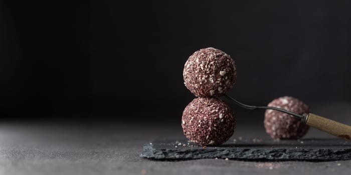 Artisan chocolate truffle candies with berry and fruit filling on dark marble background from confectionary. Handmade or handcrafted bonbons, chocolatier concept. Horizontal banner, copy space