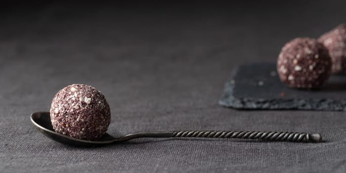 Artisan chocolate truffle candies with berry and fruit filling on dark marble background from confectionary. Handmade or handcrafted bonbons, chocolatier concept. Horizontal banner, copy space