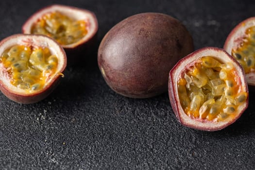 Passion fruits and its cross section with pulpy juice filled with seeds on black background. Horizontal banner photo with copy space