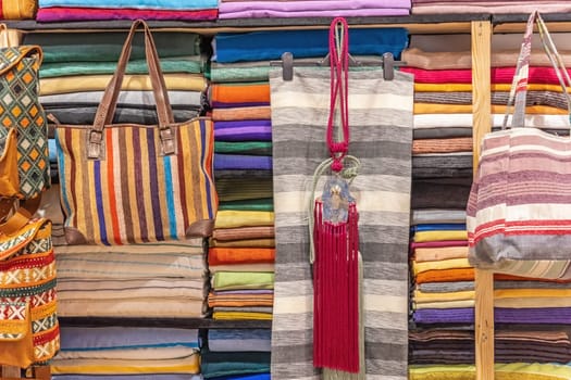 Colourful fabrics and bags displayed in a workshop connected to a shop in Fez. Morocco. Horizontally.