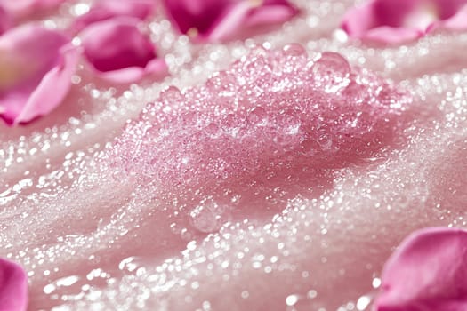 Soft pink foam fills the bath, decorated with fresh rose petals. Sparkling bubbles rise to the surface, creating a tranquil and inviting ambiance for relaxation.