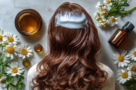 A person relaxes while receiving a nourishing hair treatment with cream on their hair. Surrounding the individual are fresh flowers and natural oils for added nourishment.