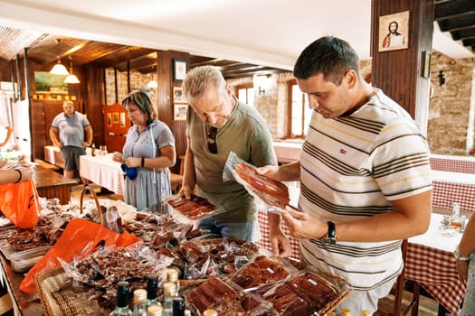Tourists select packaged cold cuts at a local market stall. High quality photo